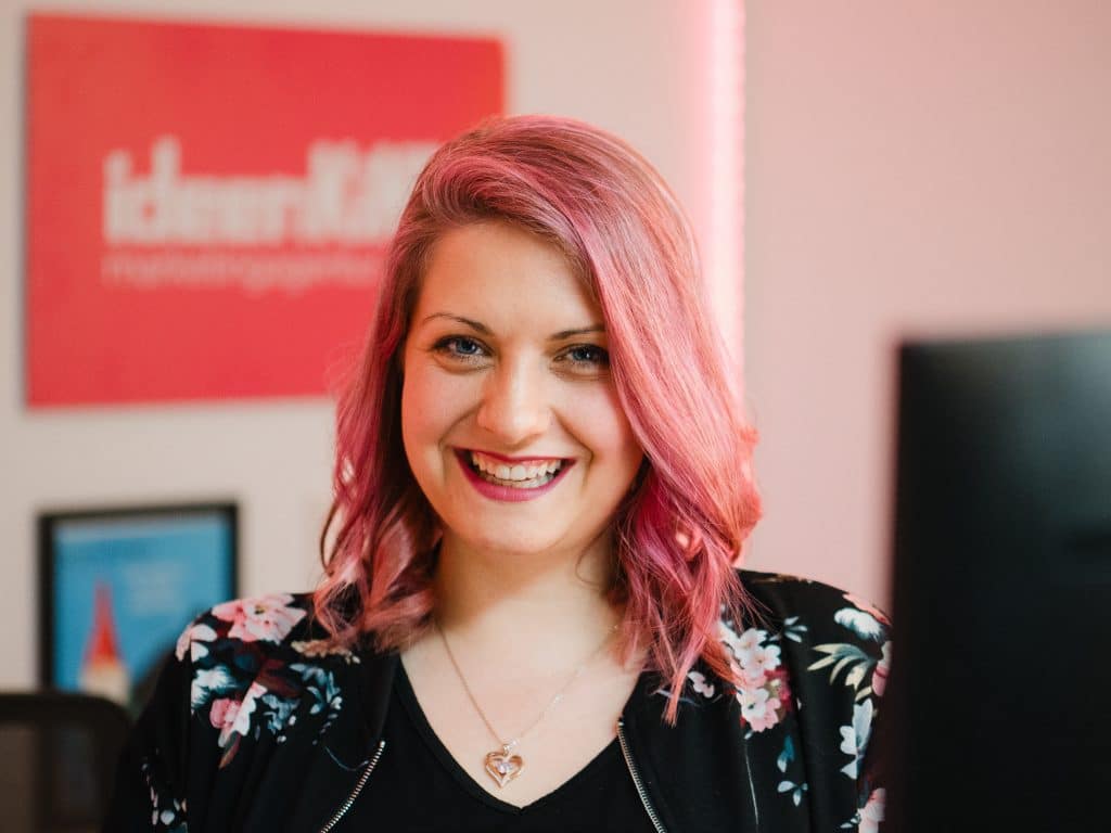 Authentisches Businessportrait einer lachenden Mitarbeiterin mit pinken Haaren. Das Bild vermittelt Offenheit, positive Unternehmenskultur und den modernen New Work Geist in der Unternehmenskommunikation. Zu sehen ist Tanja Kaltwasser Geschäftsführerin der Marketingagentur ideenKiND