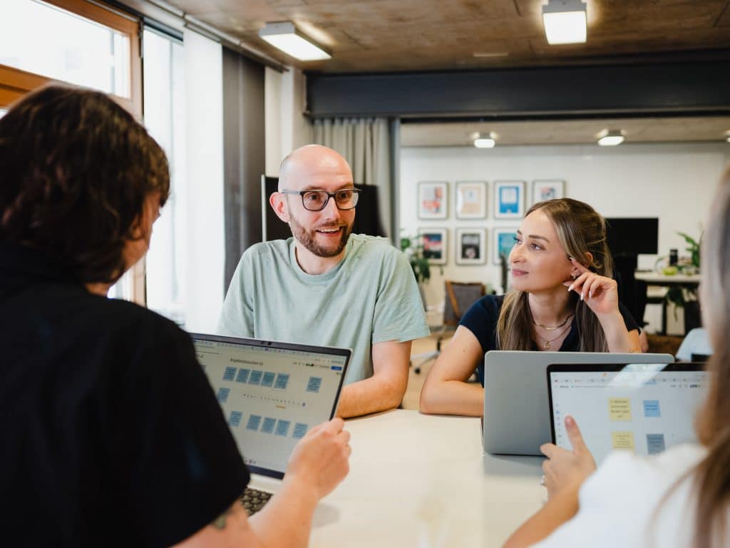Angeregtes Gespräch zwischen Mitarbeitenden des Unternehmen Fellowork aus Karlsruhe in einer mordernen Arbeitsumgebung