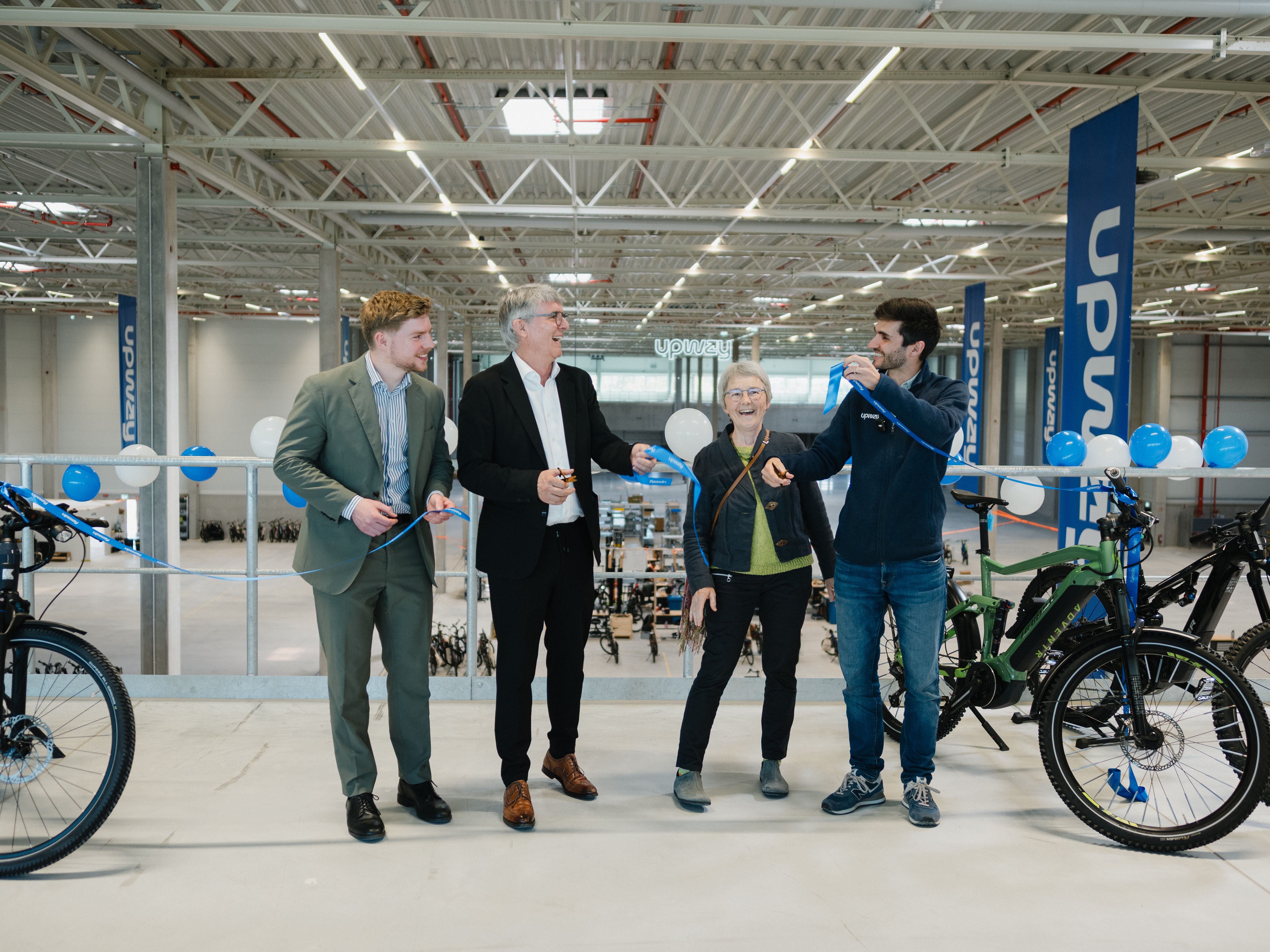 Professionelle Event- und Unternehmenskommunikation in der Region Rhein-Neckar: Tobias Roth fotografiert die feierliche Eröffnung einer E-Bike-Produktionsstätte. Hochwertige Business-Fotografie, die den Moment des Durchschneidens des Bandes dynamisch festhält.